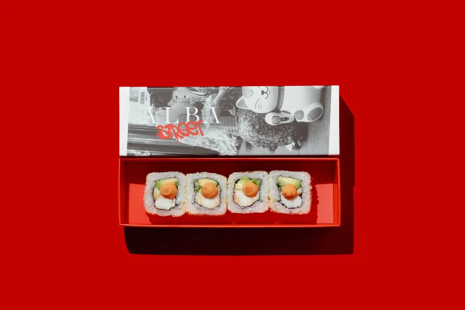 Four Crunchy California maki pieces in a red Alba Street box, held over a red backdrop at Social Distrikt, Dubai Mall